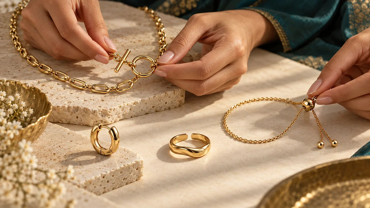 Hands handling a necklace toggle and bracelet slider beside a hinged hoop and open ring; conceptual editorial image, not ARVENIER products.