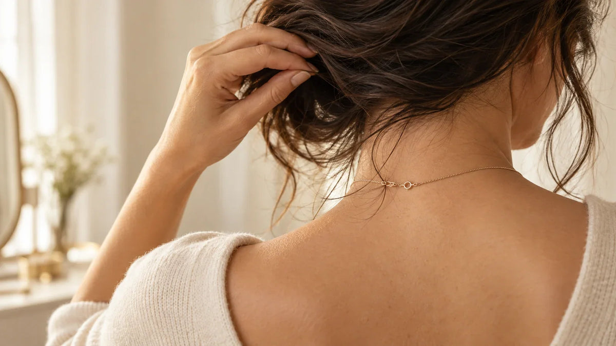 Conceptual AI-generated editorial close-up of loose hair near a generic necklace clasp at the nape; no ARVENIER product is shown.