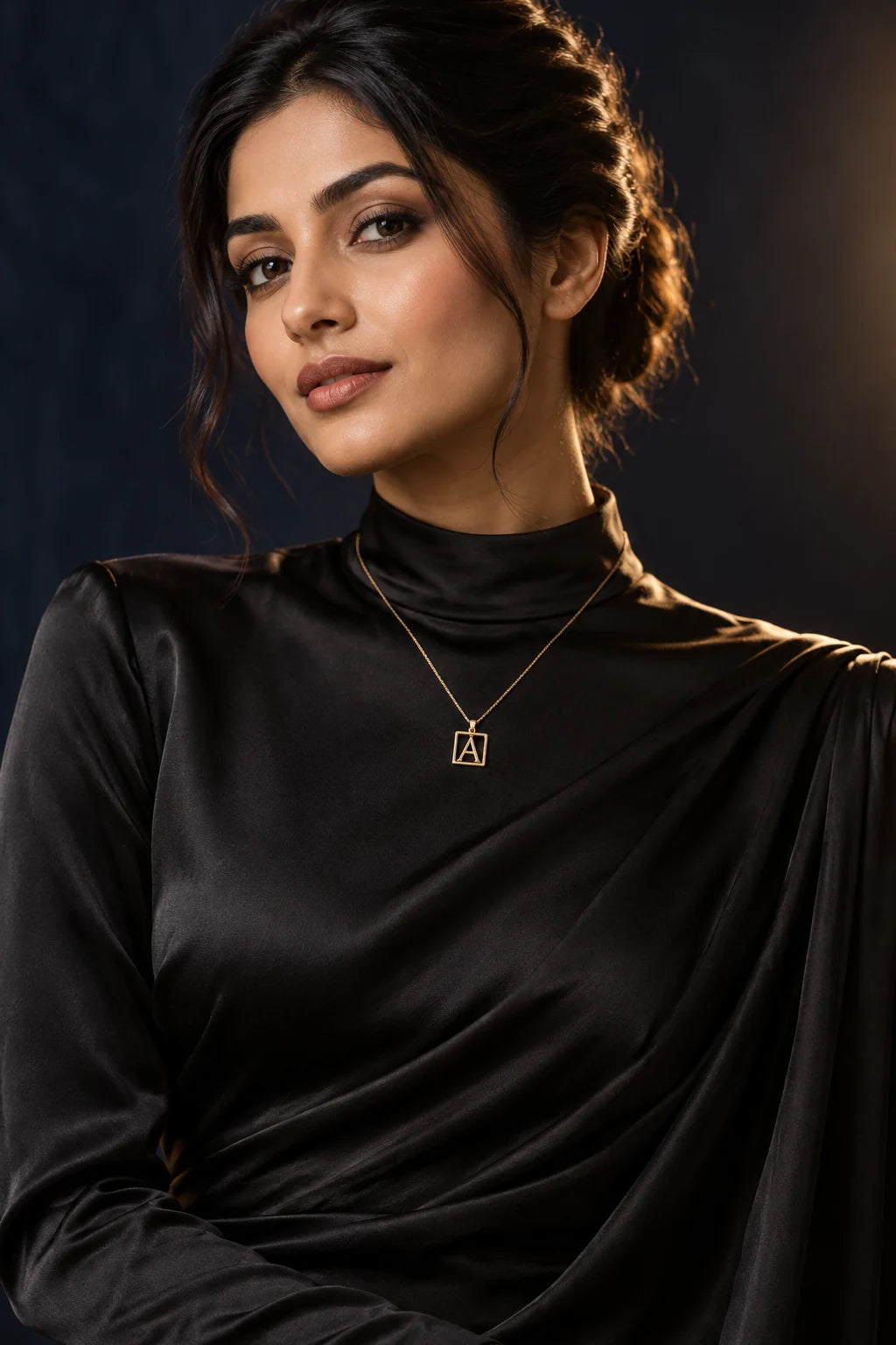 Model in black silk wearing a square gold initial pendant necklace